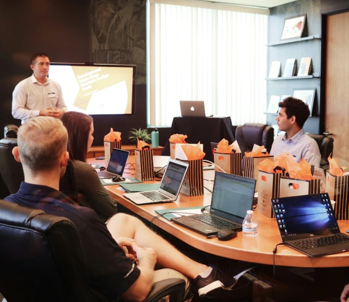 man standing in front of people sitting beside table with laptop computers